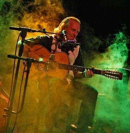 guitarist on stage sitting on a guitar stool