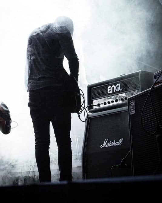 guitarist on stage with a guitar amplifier