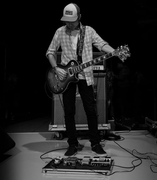 man on stage tuning guitar