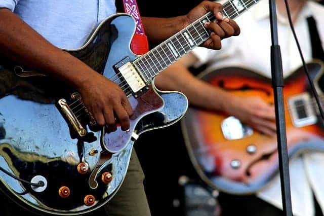 people playing semi-acoustic guitars on stage
