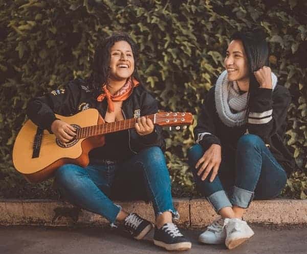 two women having fun one is strumming a guitar